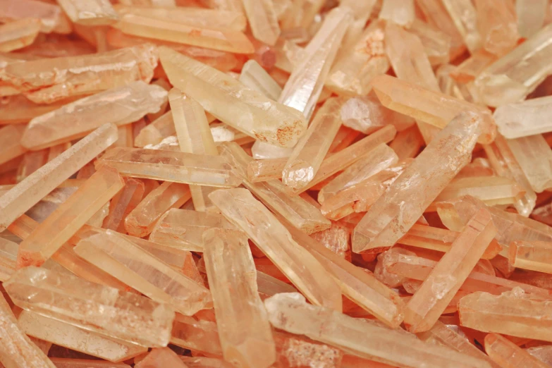 a pile of orange crystals sitting on top of a table, pexels, light pink mist, rows of razor sharp teeth, light tan, ivory