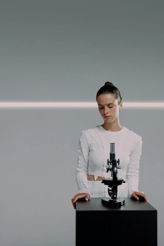 a woman standing in front of a microscope, a hologram, inspired by Anna Füssli, alicia vikander, still from a music video, hyperrealistic”, a laser rifle