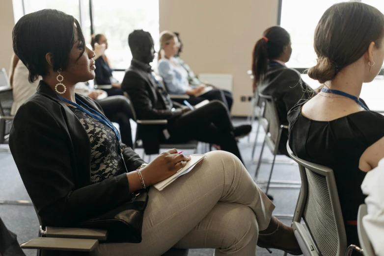 a group of people sitting in chairs in a room, profile image, digital image, teaching, female looking