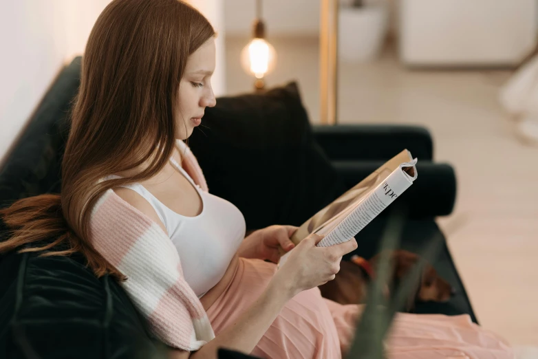 a woman sitting on a couch reading a book, a cartoon, pexels contest winner, happening, pregnant belly, side profile shot, casually dressed, magazine