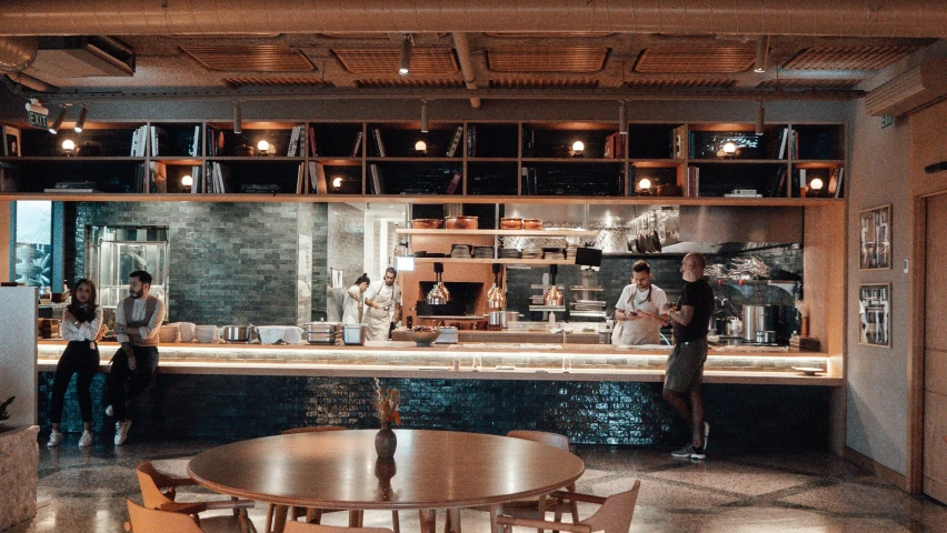 a group of people standing in a kitchen next to a table, unsplash, renaissance, woodfired, jakarta, open plan, on ocean