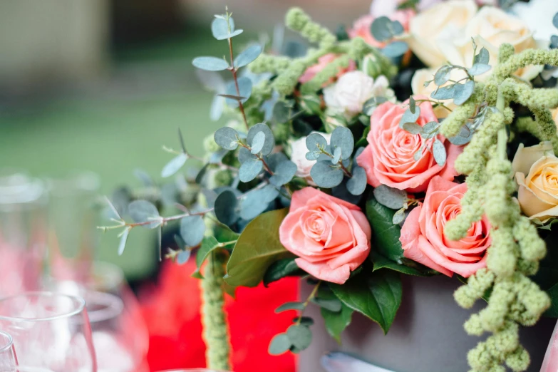 a close up of a vase of flowers on a table, trending on unsplash, al fresco, decorative roses, eucalyptus, extremely graphic