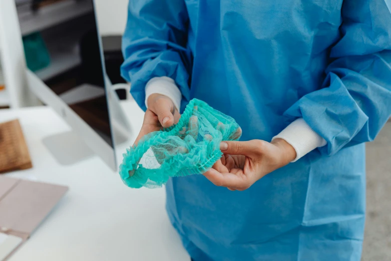 a close up of a person holding something in their hands, plasticien, surgical gown and scrubs on, laced lingerie, teal cloth, thumbnail