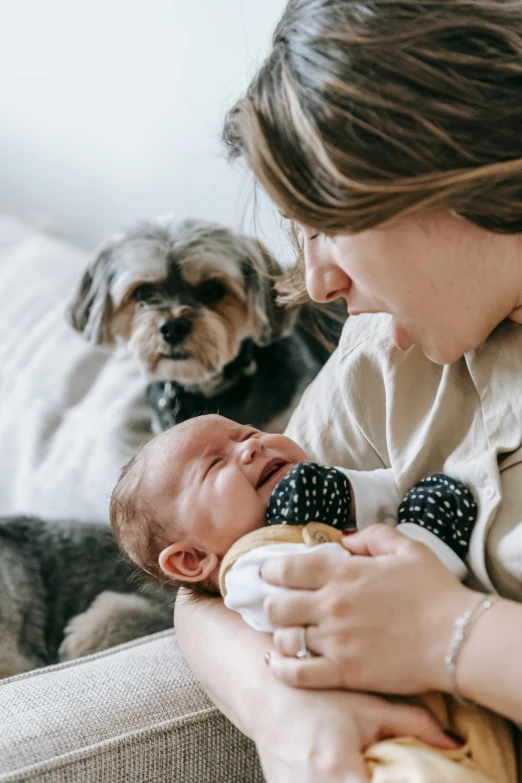 a woman sitting on a couch holding a baby and a dog, pexels contest winner, renaissance, closeup of an adorable, birth, australian, intense emotion