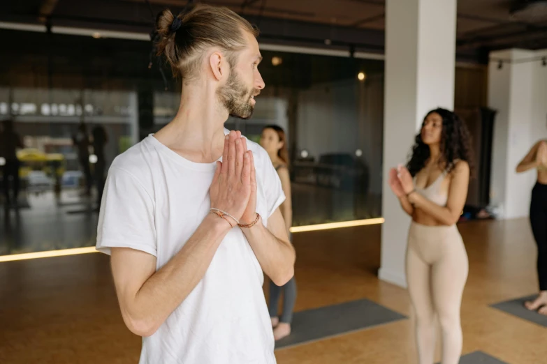 a group of people doing yoga together, pexels contest winner, man standing, looking across the shoulder, lachlan bailey, anjali mudra