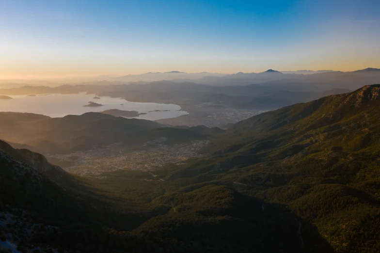 a view of the ocean from the top of a mountain, by Exekias, unsplash contest winner, hurufiyya, sunset lighting 8k, mountains and lakes, sun and shadow over a city, high quality product image”