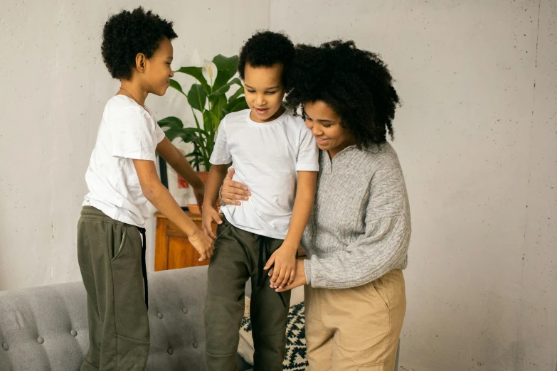 a woman standing next to two children on a couch, pexels contest winner, interactive art, wearing pants, african american, reassuring, kids playing