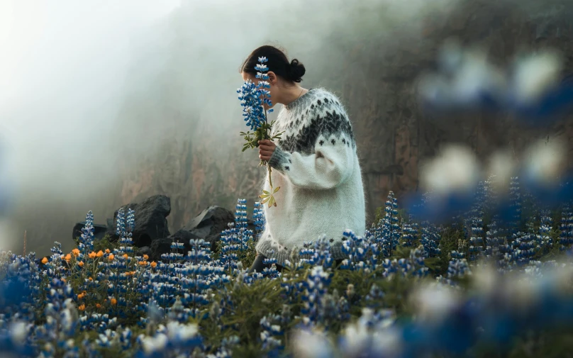 a woman standing in a field of flowers, by Louisa Matthíasdóttir, unsplash contest winner, costume with blue accents, mountain plants, wool felting art, with fog