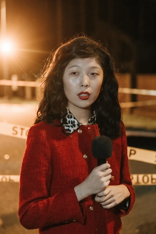 a woman in a red coat is holding a microphone, on a street at night, louise zhang, news report, looking serious