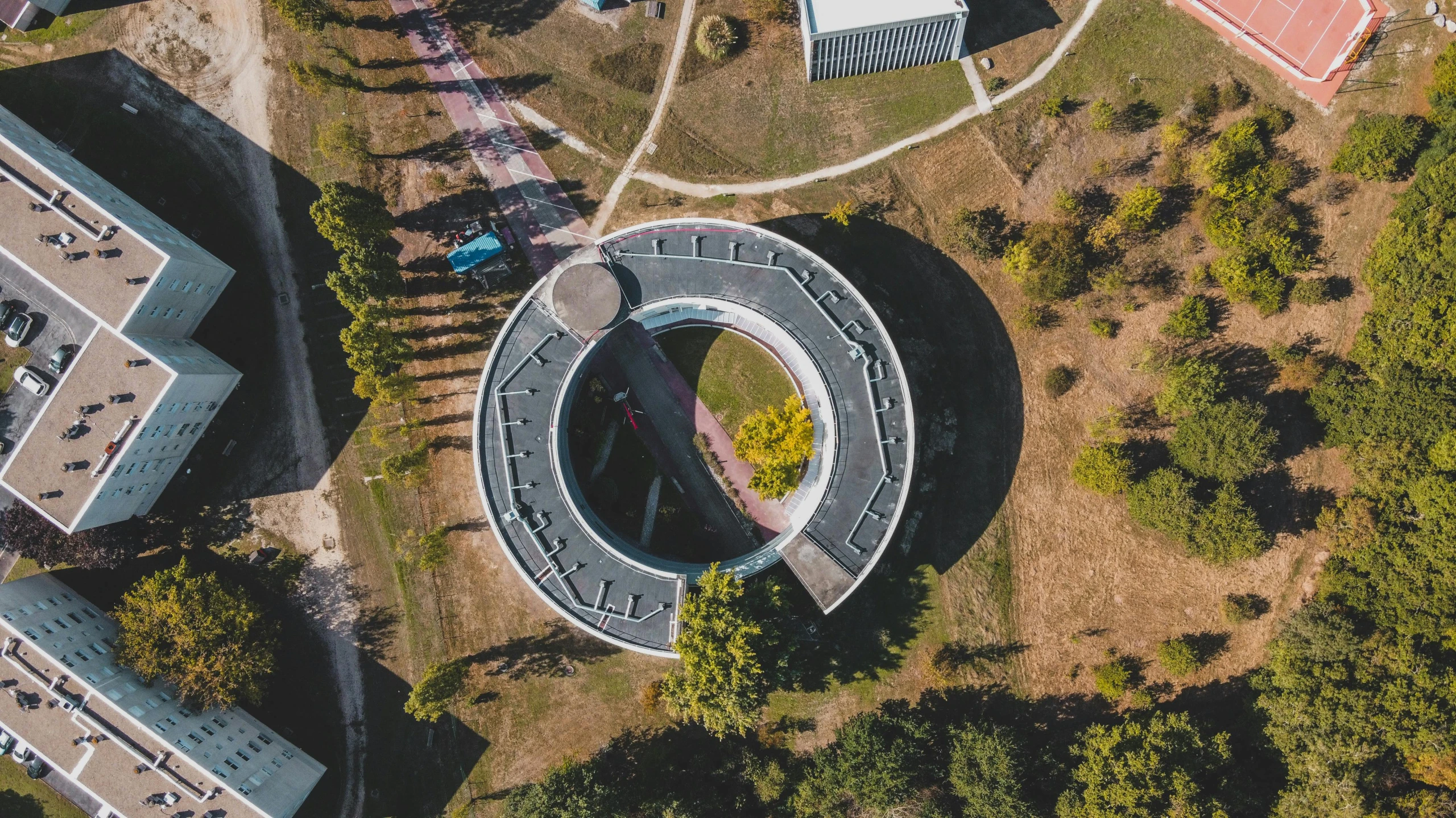 an aerial view of a building surrounded by trees, by Adam Marczyński, pexels contest winner, bauhaus, mobius strip shaped planet, ouroboros, school, museum photo