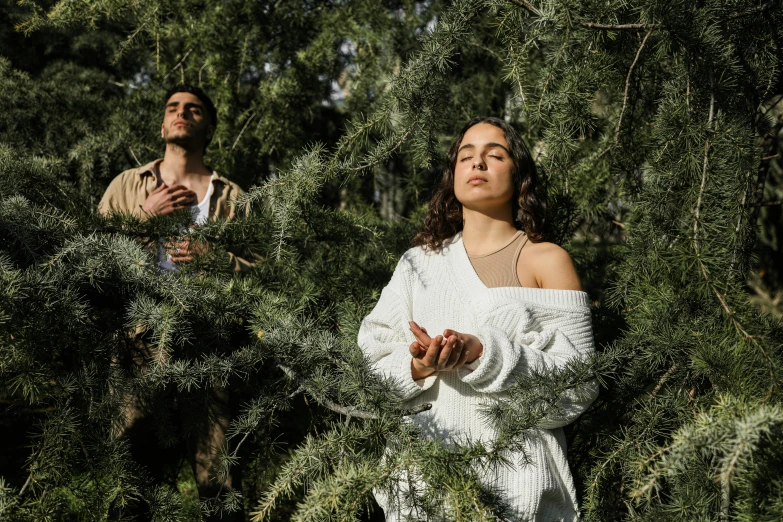 a woman standing next to a man in a forest, an album cover, pexels, renaissance, praying meditating, avan jogia angel, covered in plants, taken on iphone 14 pro