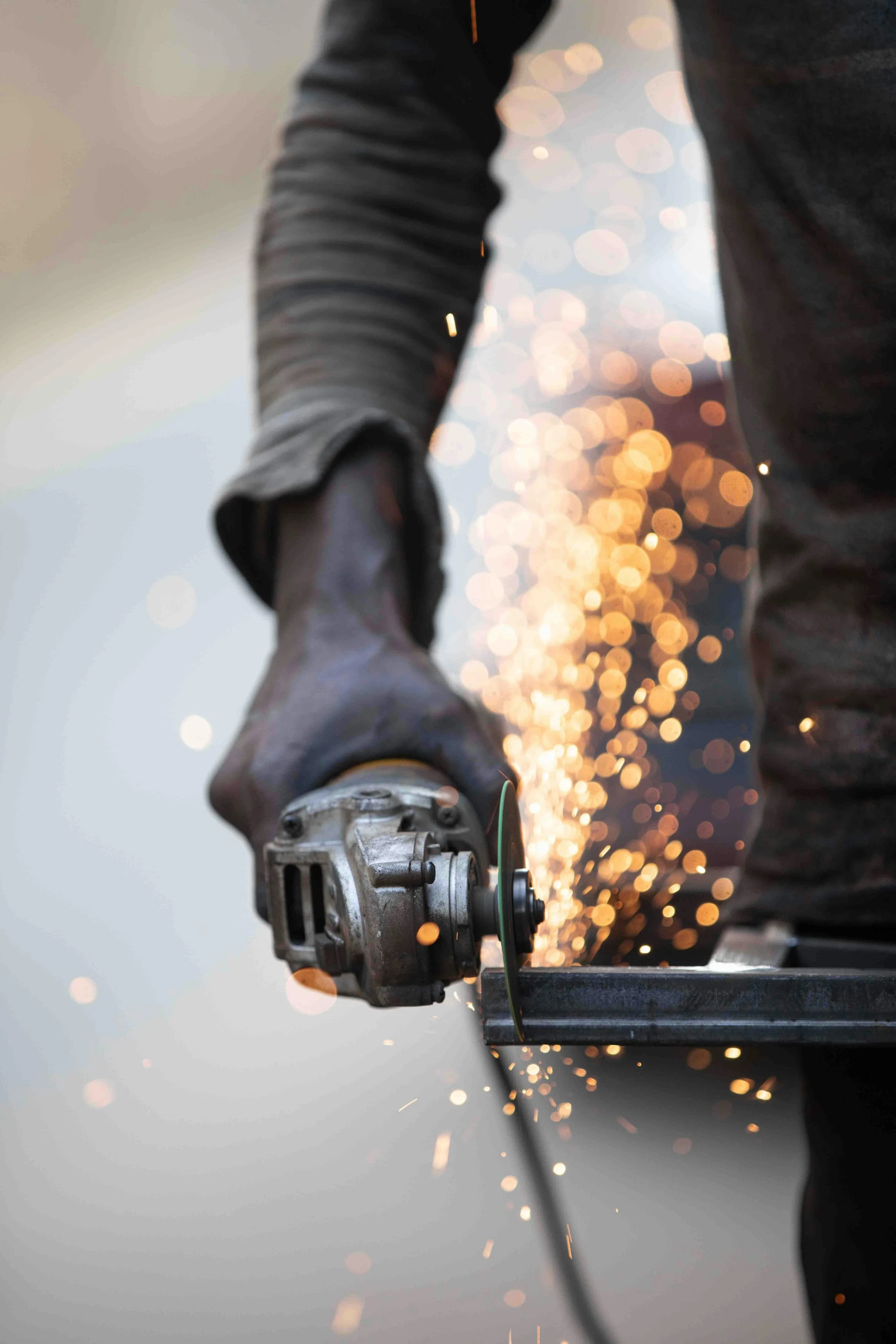 a man using a grinder on a piece of metal, by Robert Medley, pexels contest winner, renaissance, photographed for reuters, made of steel, bright lights, heavy-duty boots