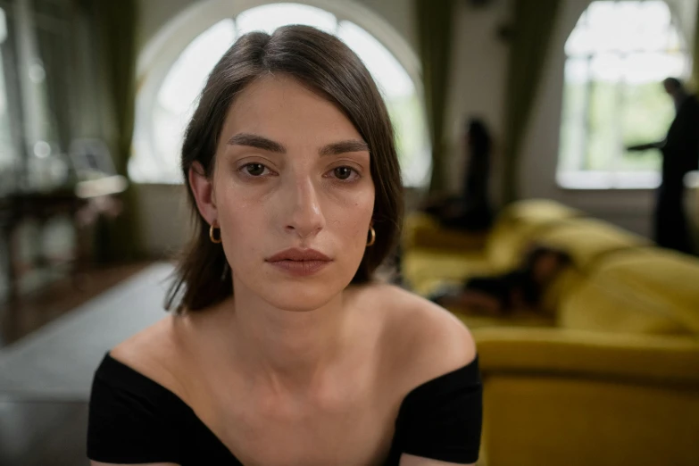 a woman sitting in a living room next to a couch, pexels contest winner, hyperrealism, big cheekbones, middle eastern skin, concerned, dua lipa