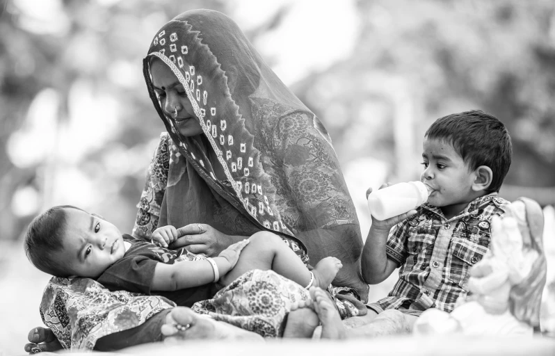 a black and white photo of a woman feeding a baby, a black and white photo, by Riza Abbasi, picnic, compassion, happy family, three