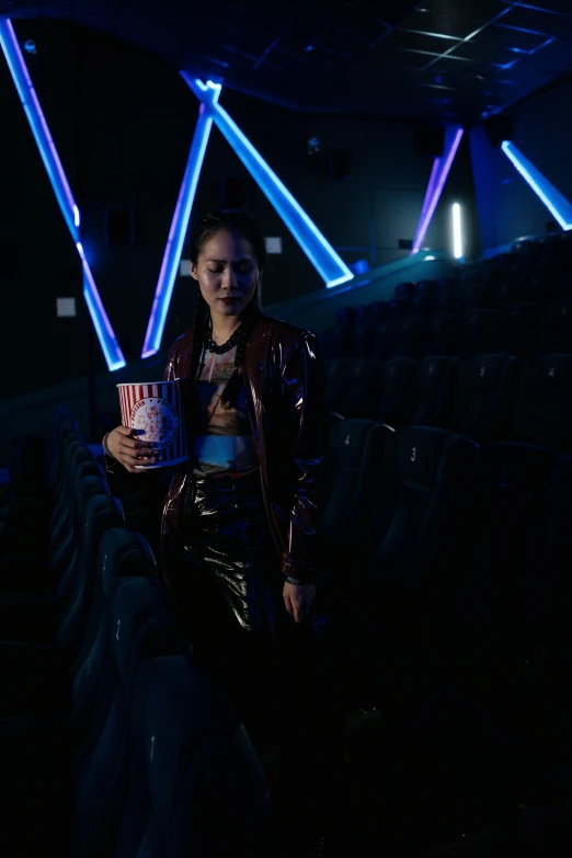 a woman sitting on the back of a bus holding a drink, a hologram, inspired by Nan Goldin, pexels contest winner, holography, wearing cyberpunk leather jacket, sitting in a movie theater, kiko mizuhara, purple scene lighting