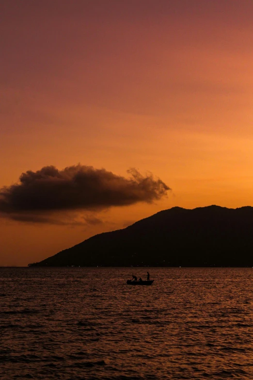 a boat floating on top of a large body of water, a picture, by Robbie Trevino, romanticism, mountains and sunset!!, silhouette :7, f/1.8, tropical atmosphere