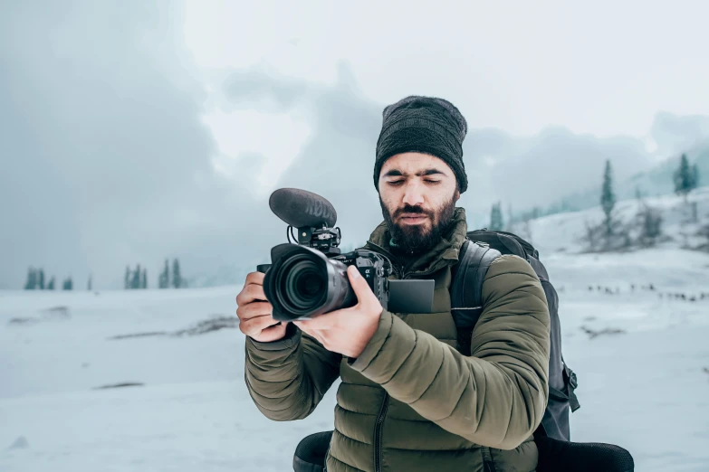 a man holding a camera in the snow, avatar image, youtuber, sony 175mm”, tourism photography