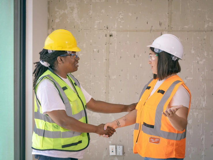 two women shaking hands on a construction site, pexels contest winner, avatar image, wearing hi vis clothing, riyahd cassiem, alexis franklin