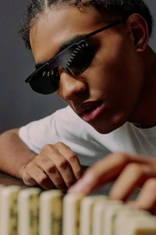 a close up of a person playing domino, an album cover, by Cosmo Alexander, trending on pexels, visual art, wearing oakley sunglasses, eating garlic bread, black teenage boy, professional modeling