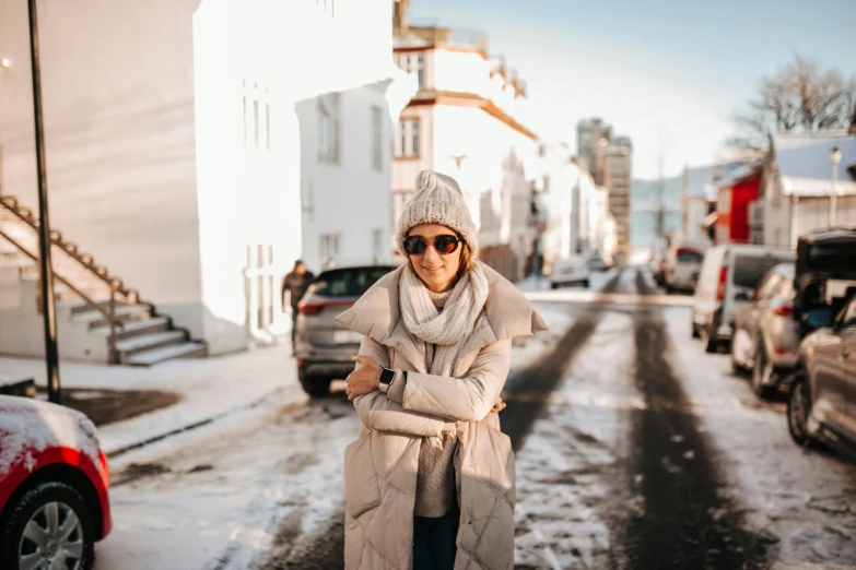 a woman standing in the middle of a snowy street, inspired by Louisa Matthíasdóttir, pexels contest winner, confident relaxed pose, sunglasses and a scarf, reykjavik, outfit : jeans and white vest