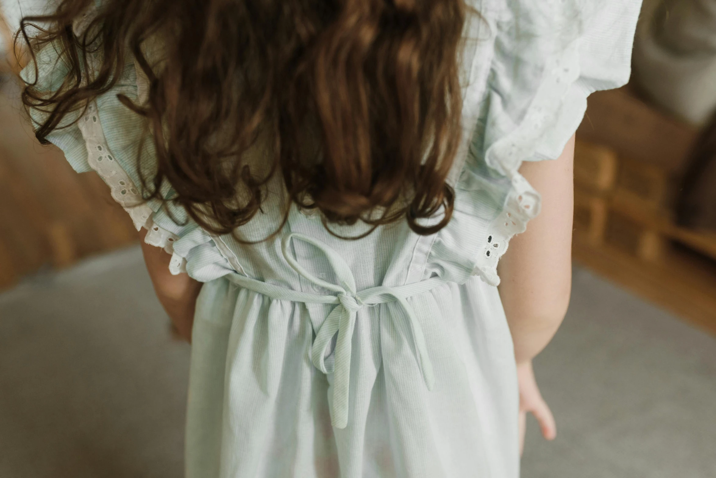 a close up of a person wearing a dress, inspired by Elsa Beskow, petite girl, soft grey and blue natural light, her back is to us, precious moments