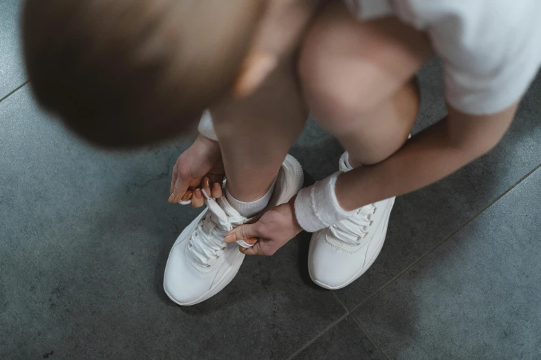 a close up of a person tying a shoe, wearing white sneakers, girl wearing uniform, chalk white skin, profile image