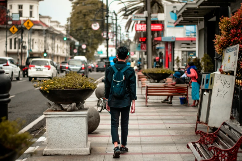 a person with a backpack walking down a sidewalk, by Niko Henrichon, pexels contest winner, south jakarta, background image, in a square, male teenager