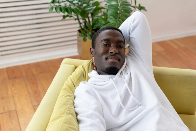 a man that is laying down on a couch, inspired by Edward Okuń, pexels contest winner, wearing a track suit, avatar image, african man, white hue