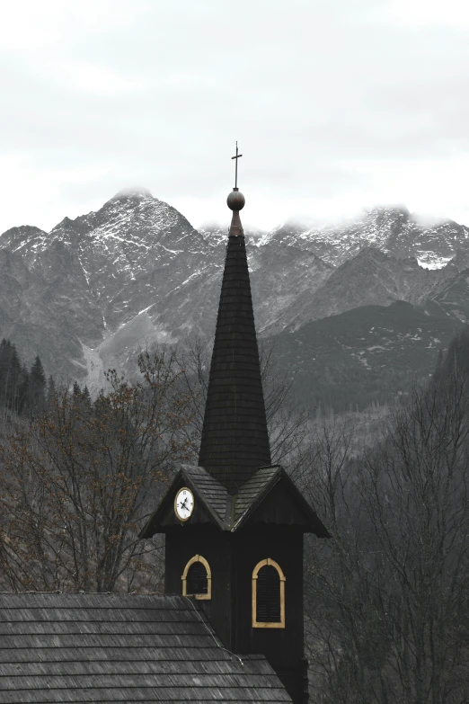 a black and white photo of a church with mountains in the background, an album cover, inspired by Emil Fuchs, pexels contest winner, baroque, clock, church in the wood, in muted colours, heavy winter aesthetics