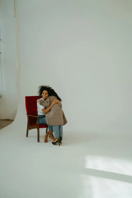 a woman sitting on a red chair in a white room, by Lily Delissa Joseph, pexels contest winner, hugging her knees, ashteroth, 15081959 21121991 01012000 4k, plain background