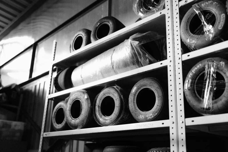 a black and white photo of a shelf full of rolls of duct tape, by Frederik Vermehren, mingei, smokey tires, formula 1 garage, museum archive photo, getty images