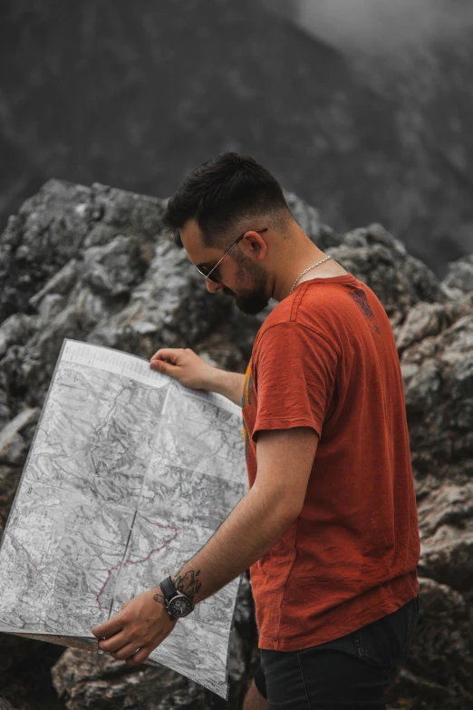 a man standing on top of a mountain holding a map, pexels contest winner, bearded, grey, stonepunk, plan