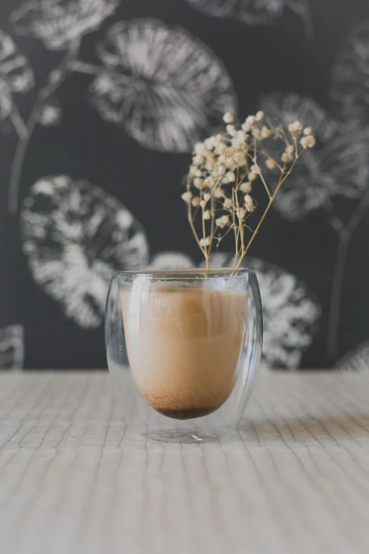 a cup of coffee sitting on top of a wooden table, inspired by Jacopo Bellini, unsplash, arabesque, plants in a glass vase, manuka, detailed product image, portrait shot