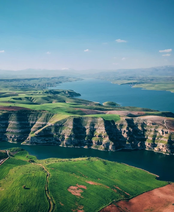 a large body of water sitting on top of a lush green hillside, by Daren Bader, pexels contest winner, hurufiyya, mesopotamic, with rolling hills, beautiful lake, epic land formations
