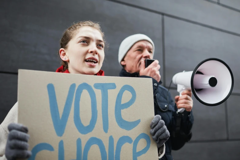 a man and a woman holding a sign and a megaphone, a photo, shutterstock, chloë grace moretz, election poster, thumbnail, profile picture 1024px