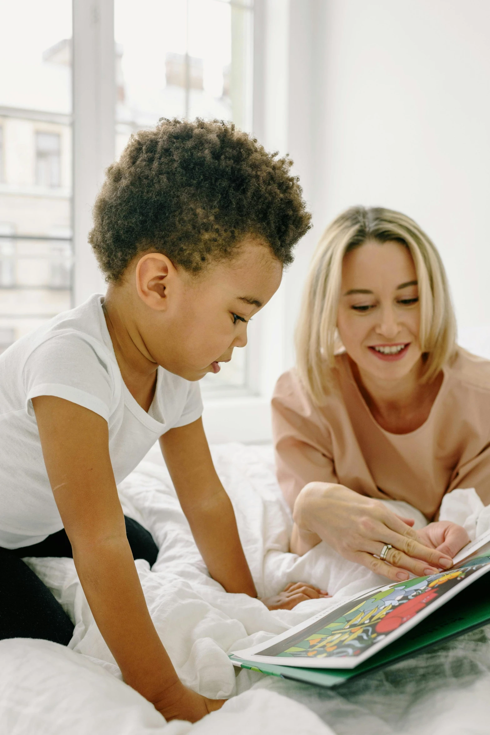 a woman reading a book to a child on a bed, diverse, looking smart, coloured, thumbnail