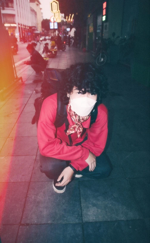 a person kneeling down on the side of a street, an album cover, inspired by Elsa Bleda, unsplash, vanitas, he‘s wearing a red neckerchief, no face mask, low quality photo, ((red)) baggy eyes