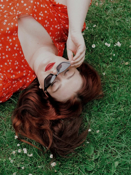 a woman laying on top of a lush green field, by Julia Pishtar, trending on pexels, wearing red tainted glasses, auburn hair, ✨🕌🌙, profile image