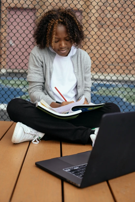 a woman sitting on top of a wooden floor next to a laptop computer, trending on pexels, academic art, black teenage boy, school courtyard, tournament, writing in journal