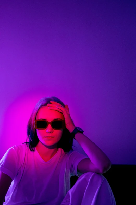 a woman sitting in front of a purple light, trending on unsplash, color field, androgynous male, wearing shades, joe keery, flashing lights