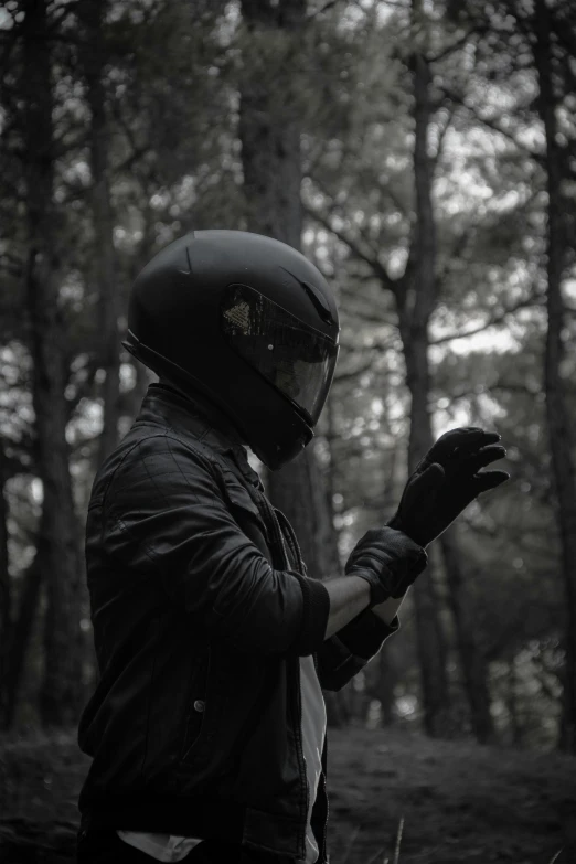 a black and white photo of a person wearing a helmet, unsplash, in dark woods, black leahter gloves, [ cinematic, album