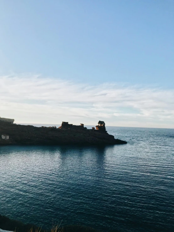 a small island in the middle of a body of water, profile image, castle in the distance, a photo of the ocean, low quality photo