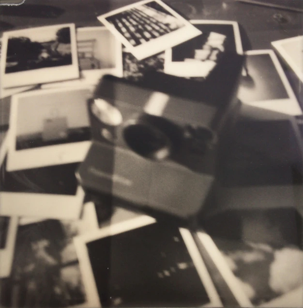 a pile of black and white photos sitting on top of a table, a polaroid photo, inspired by Louis Faurer, camera obscura, album cover, low quality photo, camera looking down upon