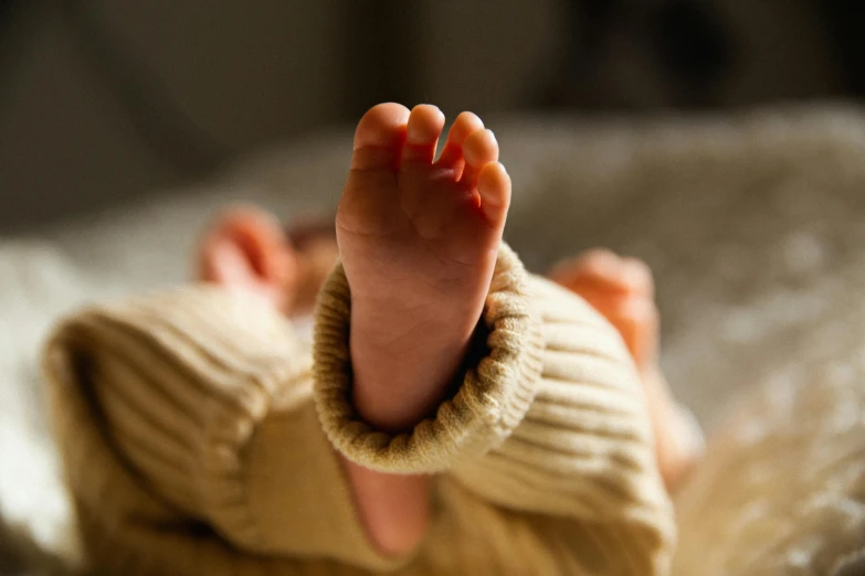 a close up of a person's feet on a bed, trending on pexels, young child, brown, warmly lit, maternity feeling