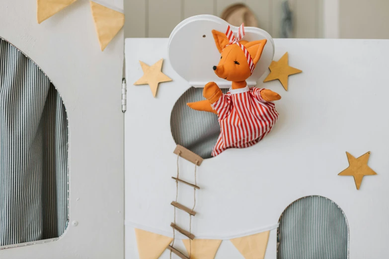 a teddy bear sitting on top of a cardboard house, inspired by The Family Circus, orange and white, hung above the door, playing with a fox, activity play centre