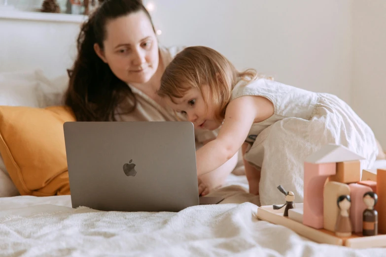 a woman and a child on a bed with a laptop, by Carey Morris, pexels, avatar image, jellycat, tiny details, people at work