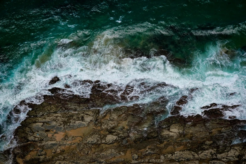 a large body of water next to a rocky shore, by Peter Churcher, pexels contest winner, close-up from above, ocean swells, manly, brown