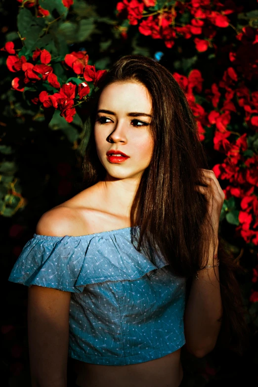 a woman standing in front of a bush of red flowers, an album cover, by Julia Pishtar, pexels contest winner, isabela moner, headshot profile picture, light blue dress portrait, 5 0 0 px models