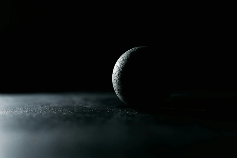 a close up of a tennis ball on a table, inspired by Michal Karcz, unsplash contest winner, digital art, vantablack, moon surface, blackened space, 8 k render