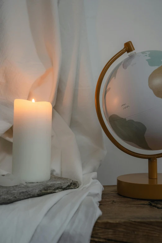 a candle sitting on top of a table next to a globe, soft white rubber, pillar, environmental shot, warm features